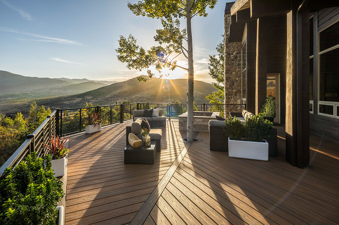 A Trex Transcend deck in Havana Gold overseeing a gorgeous mountain landscape with the sun setting over the mountain and leaving long shadows on the deck.